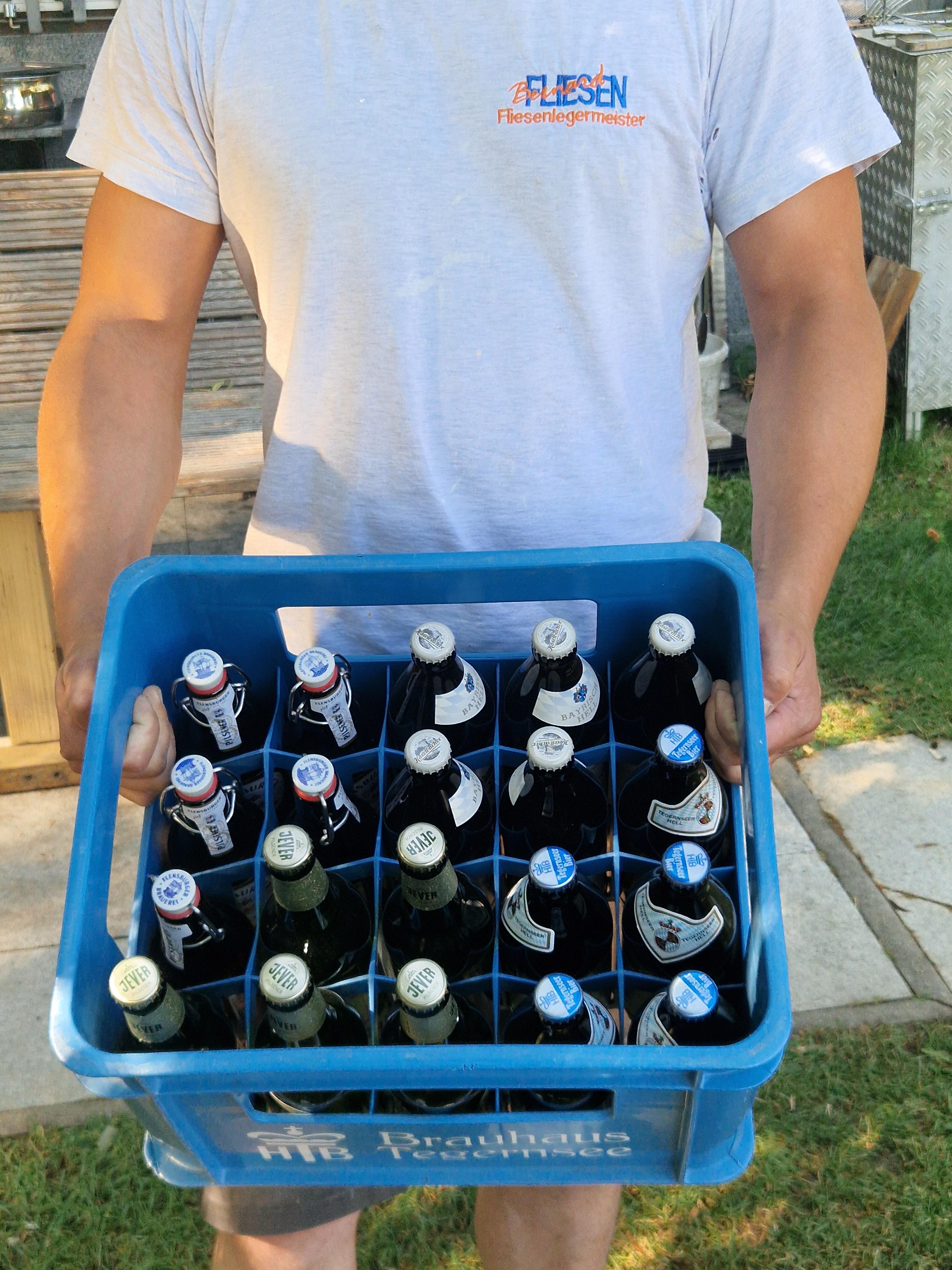 Kunde überreicht eine Kiste Bier als Dankeschön für saubere Fliesenarbeit