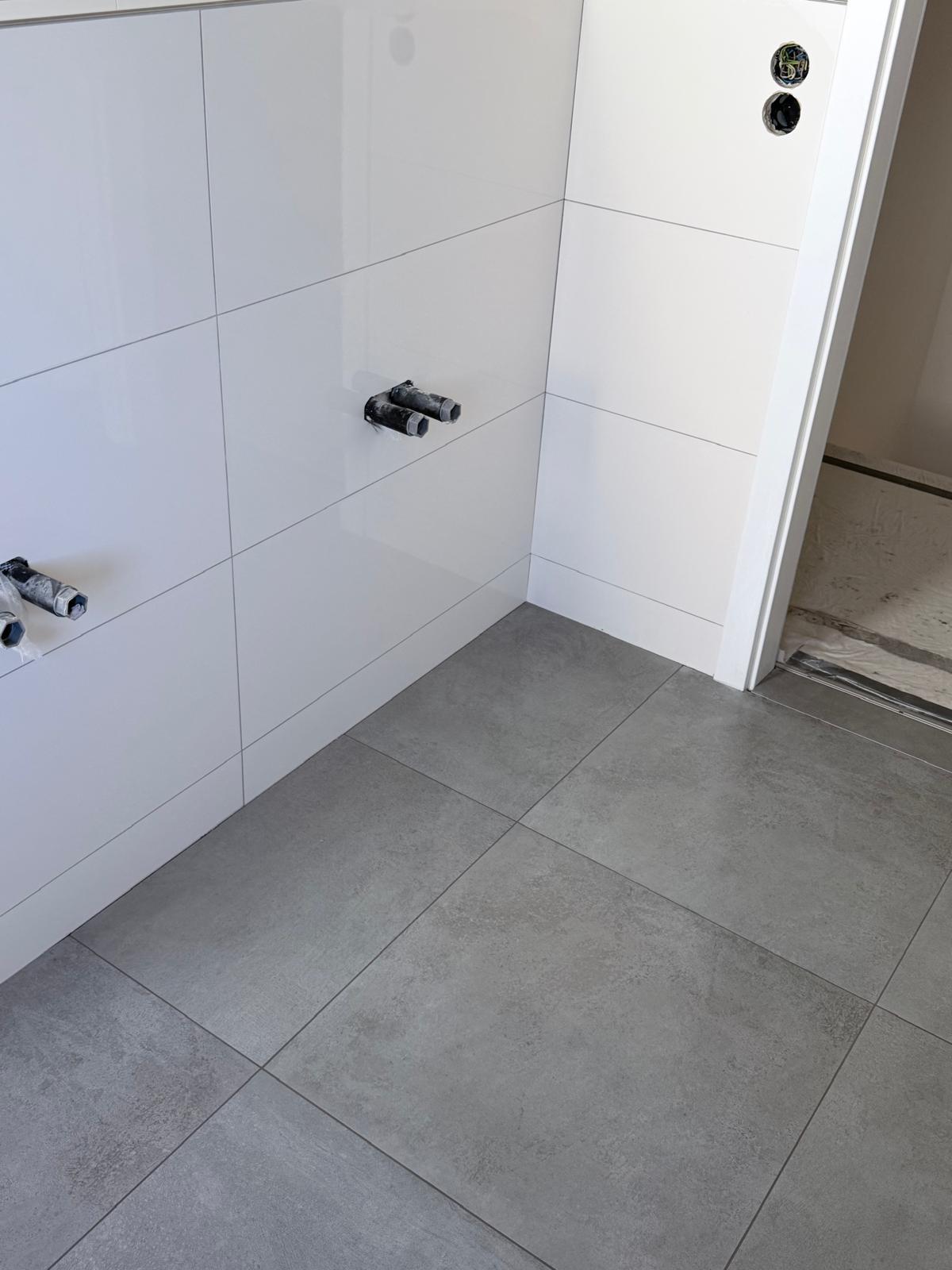 Badezimmer in Vaihingen an der Enz mit weißen Wandfliesen und grauem Boden